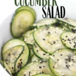 up close shot of sliced cucumbers with sesame seeds in a bowl with title