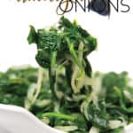white bowl of sauteed spinach with caramelized onions with a fork with some on it