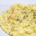 white bowl of mustard potato salad with parsley on top