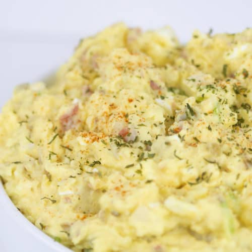 white bowl of mustard potato salad with parsley on top
