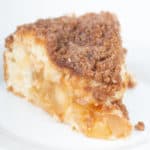 piece of apple cinnamon crumb cake with icing on top on a white plate