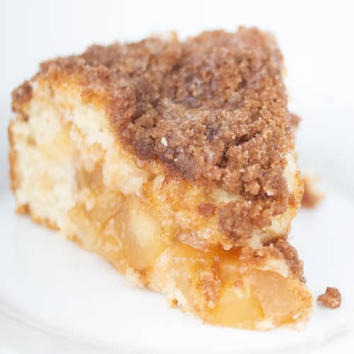 piece of apple cinnamon crumb cake with icing on top on a white plate