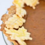a pumpkin pie in a glass pan with leaf cut outs of crust