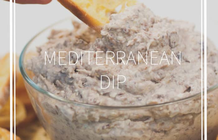 a glass bowl of whipped cheese with olives and artichokes and toasted bread
