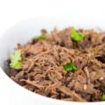 white bowl of shredded slow cooker beef barbacoa with cilantro