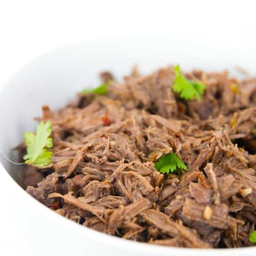 white bowl of shredded slow cooker beef barbacoa with cilantro