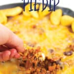 frito chili pie dip on a corn chip with dip in a pan in the background