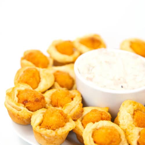 white plate of mini biscuit cups with chicken with a bowl of gravy