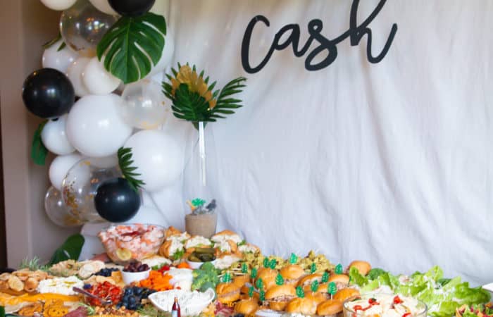 balloon arch with white backdrop with a grazing table full of food