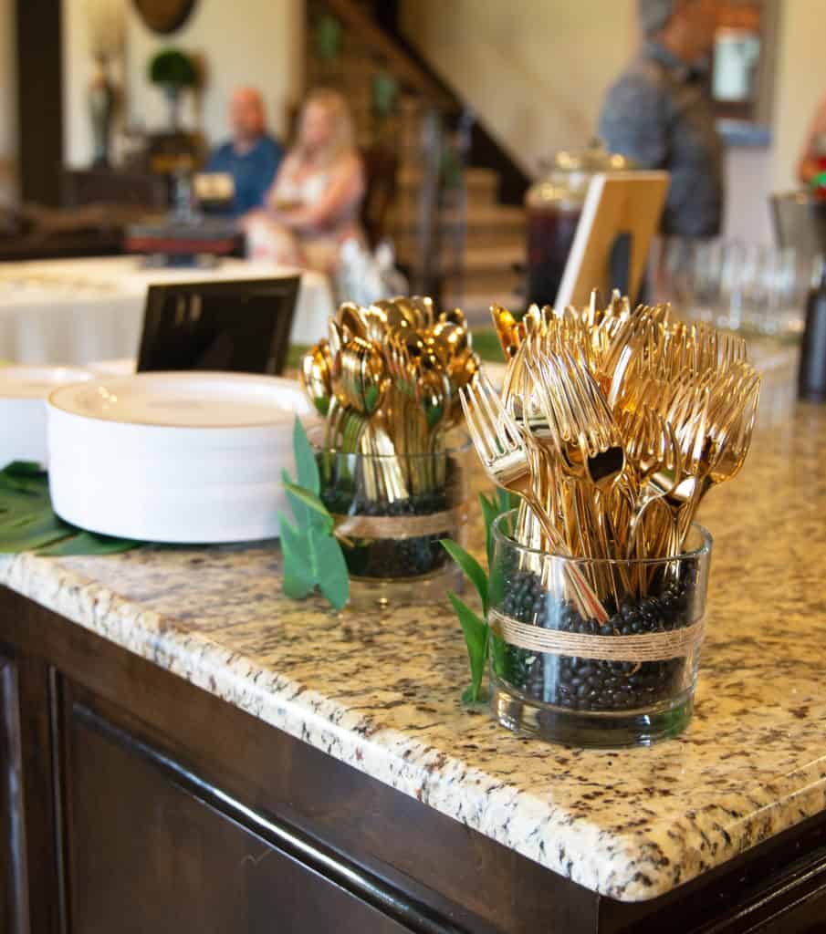 plastic plates on palm leaves with vases with gold plastic silverware on a kitchen counter