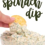 a glass bowl with spicy ranch spinach dip in it dipping a cracker in the dip