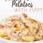 plate of creamy scalloped potatoes with ham with sliced potatoes, ham and a cheese sauce
