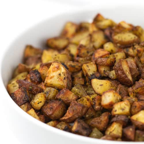 white bowl of roasted zesty italian potatoes with parsley sprinkled on top