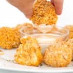 a white plate of buffalo chicken quinoa bites with a bowl of ranch dressing dipping in