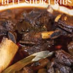 pot of red wine braised beef short ribs cooking with herbs and sauce
