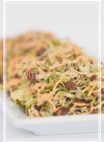 white plate of shaved brussels sprouts with spicy mayo drizzled on top