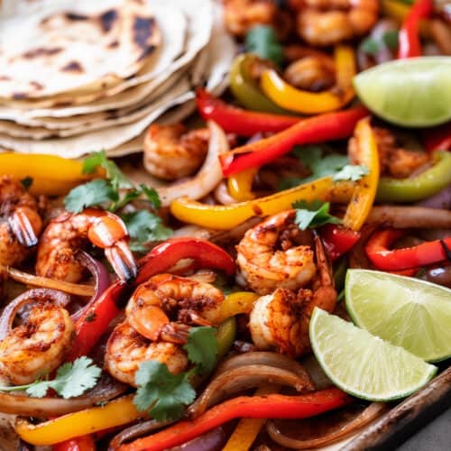 a pan of zesty shrimp sheet pan fajitas with grilled bell peppers and onions