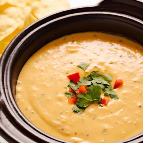 a crockpot of chorizo queso dip with garnish on top