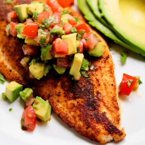 a tilapia filet seasoned and cooked with a chunky avocado salsa on top