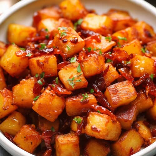 a bowl of Spicy Sriracha Honey Bacon Potatoes with green herb garnish