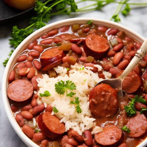 bowl of Ultimate Beans & Rice with sausage and fresh herbs on top