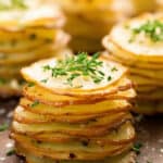 thin sliced potatoes for Stacked Herb-Cheese Potatoes with green garnish on top