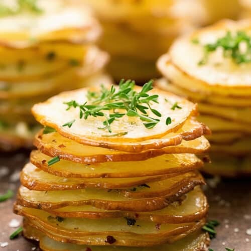 thin sliced potatoes for Stacked Herb-Cheese Potatoes with green garnish on top