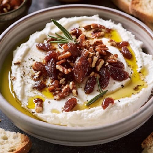 a photo of Whipped Goat Cheese Bliss with chopped dried dates, chopped pecans and olive oil on top with french bread on the side
